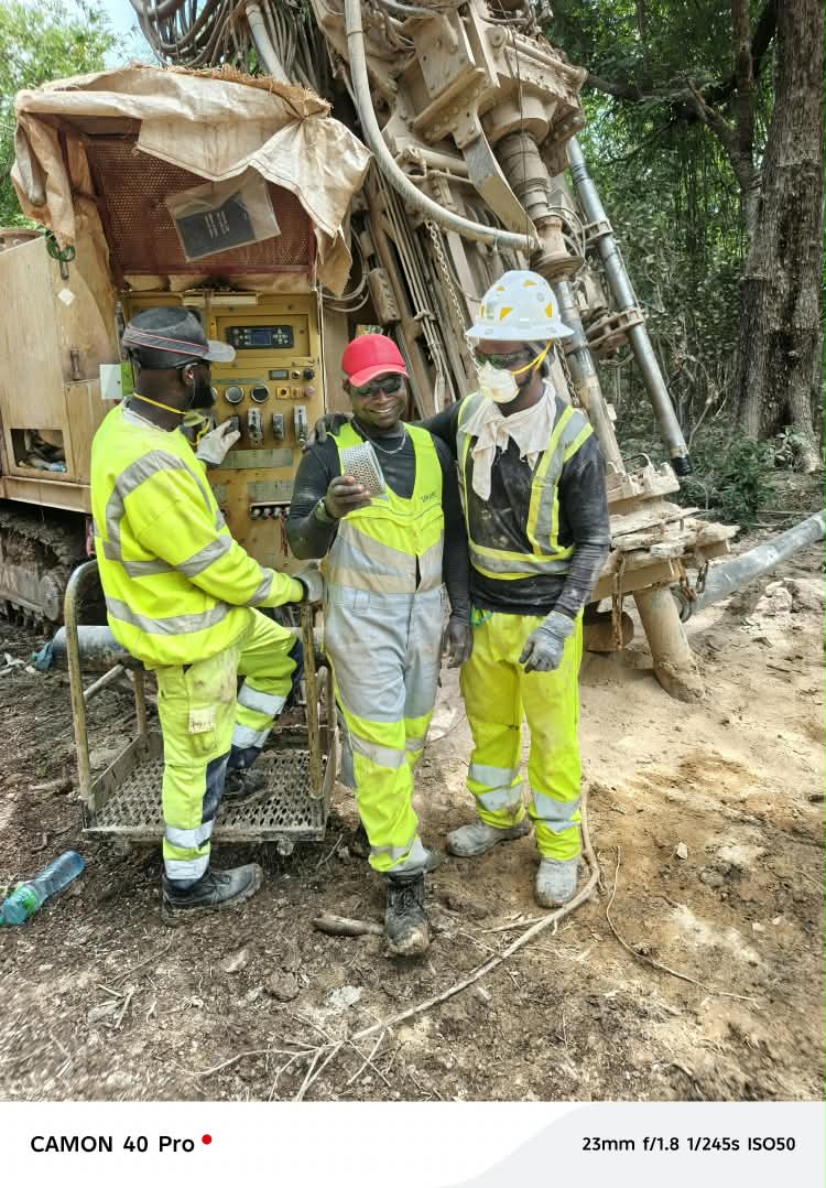 Trois collaborateurs en équipements de protection devant une installation de forage